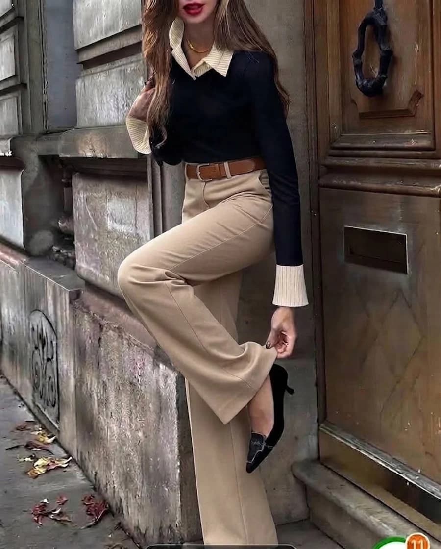 Women's autumn outfit: black sweater over a cream shirt with tan wide-leg trousers