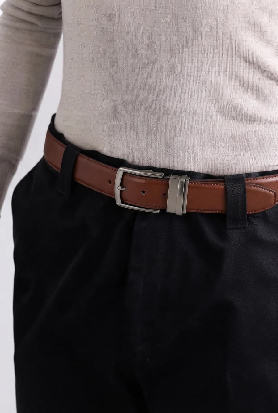 Men's cognac leather belt with black trousers and a tucked cream knit shirt