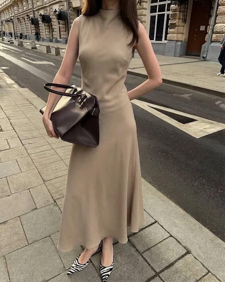 Quiet luxury outfit: beige sleeveless midi dress with a structured brown leather tote