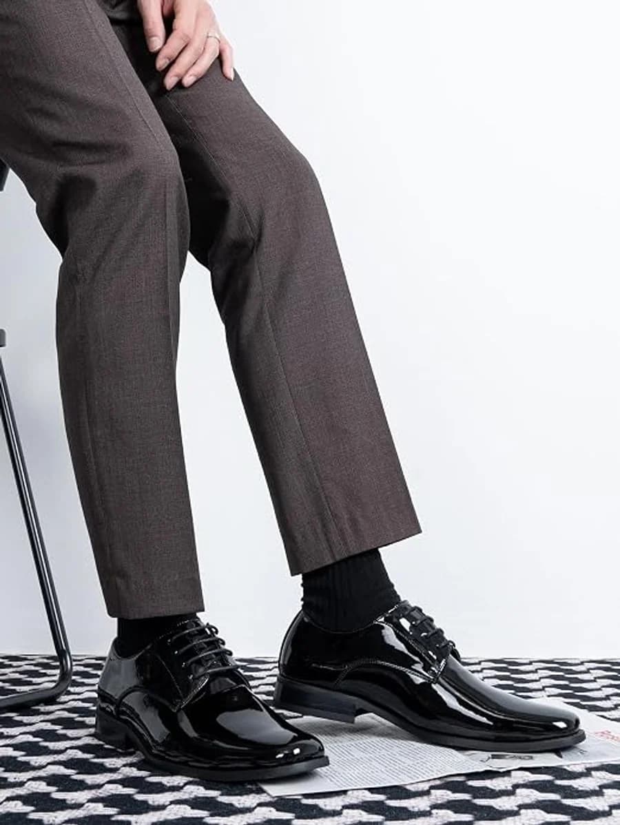 Men's black patent leather dress shoes with charcoal trousers and black socks