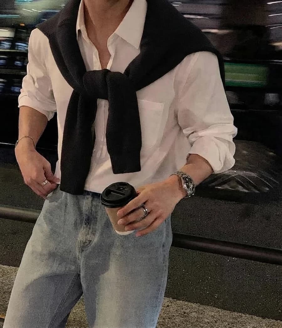 Men's spring outfit: white shirt with a sweater over the shoulders and light denim