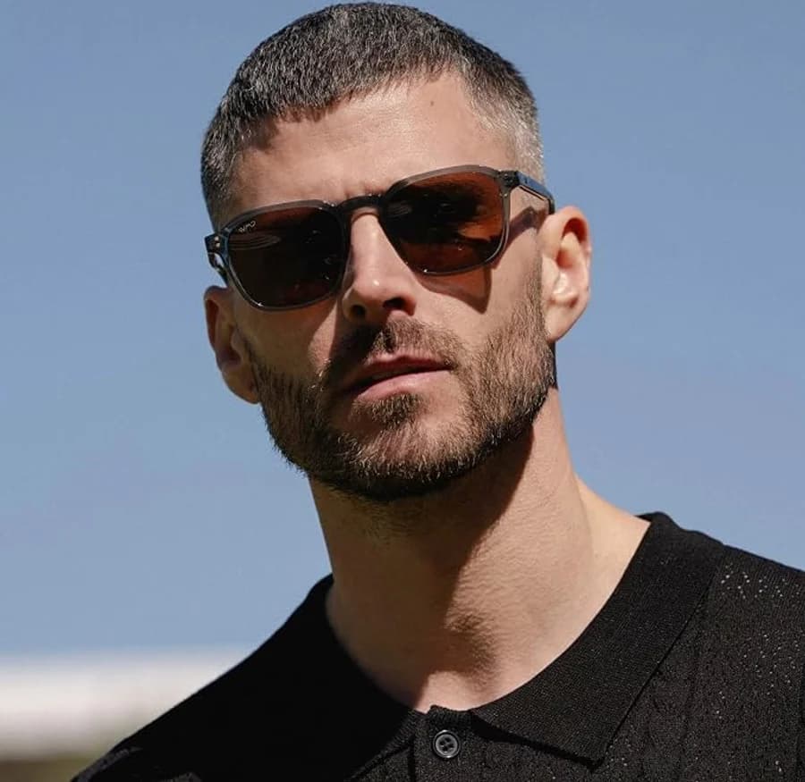 Men's smoke grey rectangular sunglasses with a black polo shirt against a blue sky