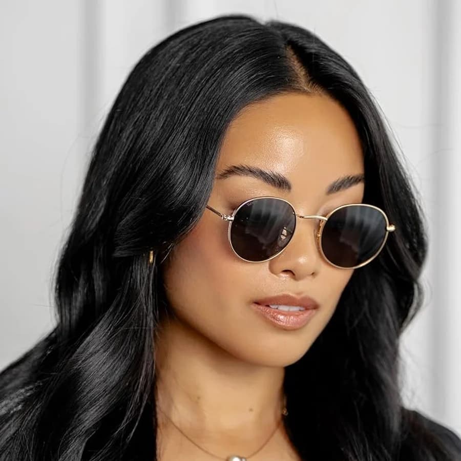 Women's round gold-frame sunglasses with dark lenses and wavy dark hair