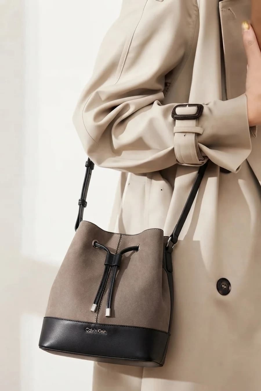 Women's brown leather bucket bag with a cream cardigan and white trousers