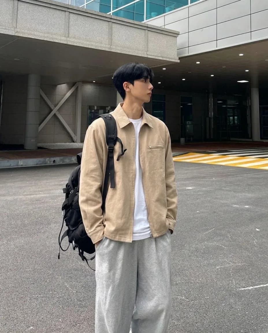 Beige zip overshirt over a white T-shirt, with grey sweatpants and a black backpack