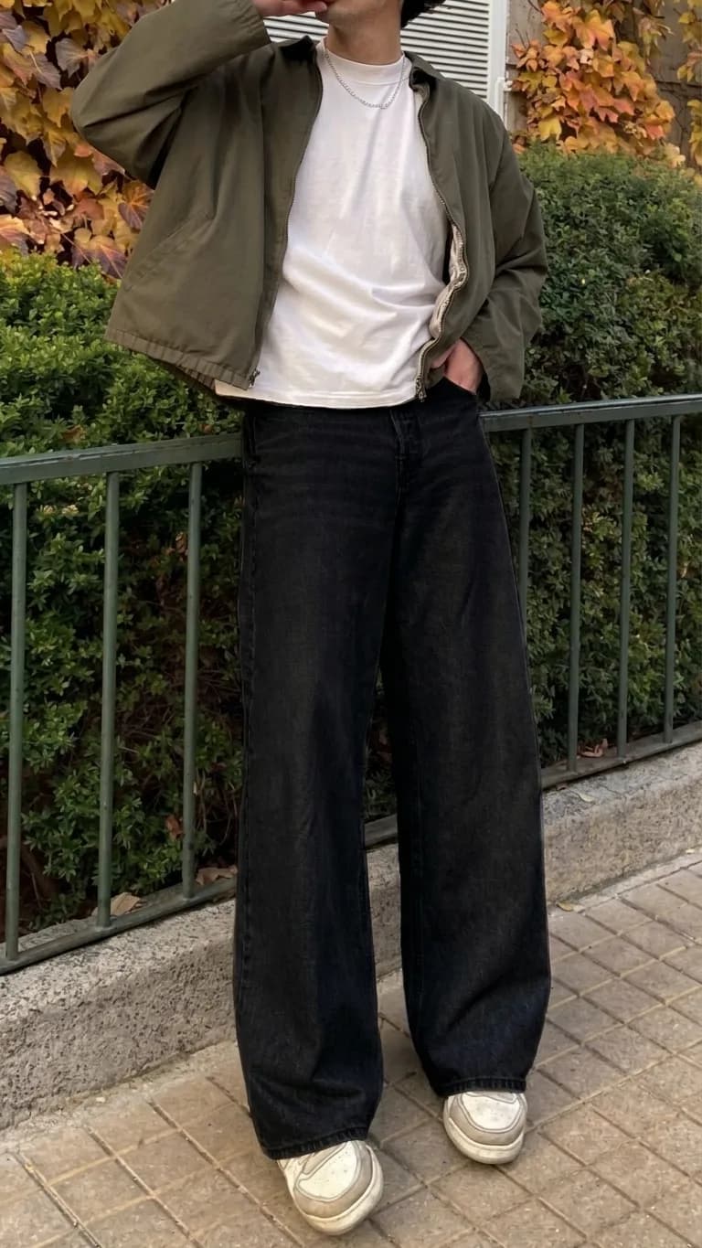 Wide black jeans worn with a white T-shirt, an olive jacket, and white sneakers