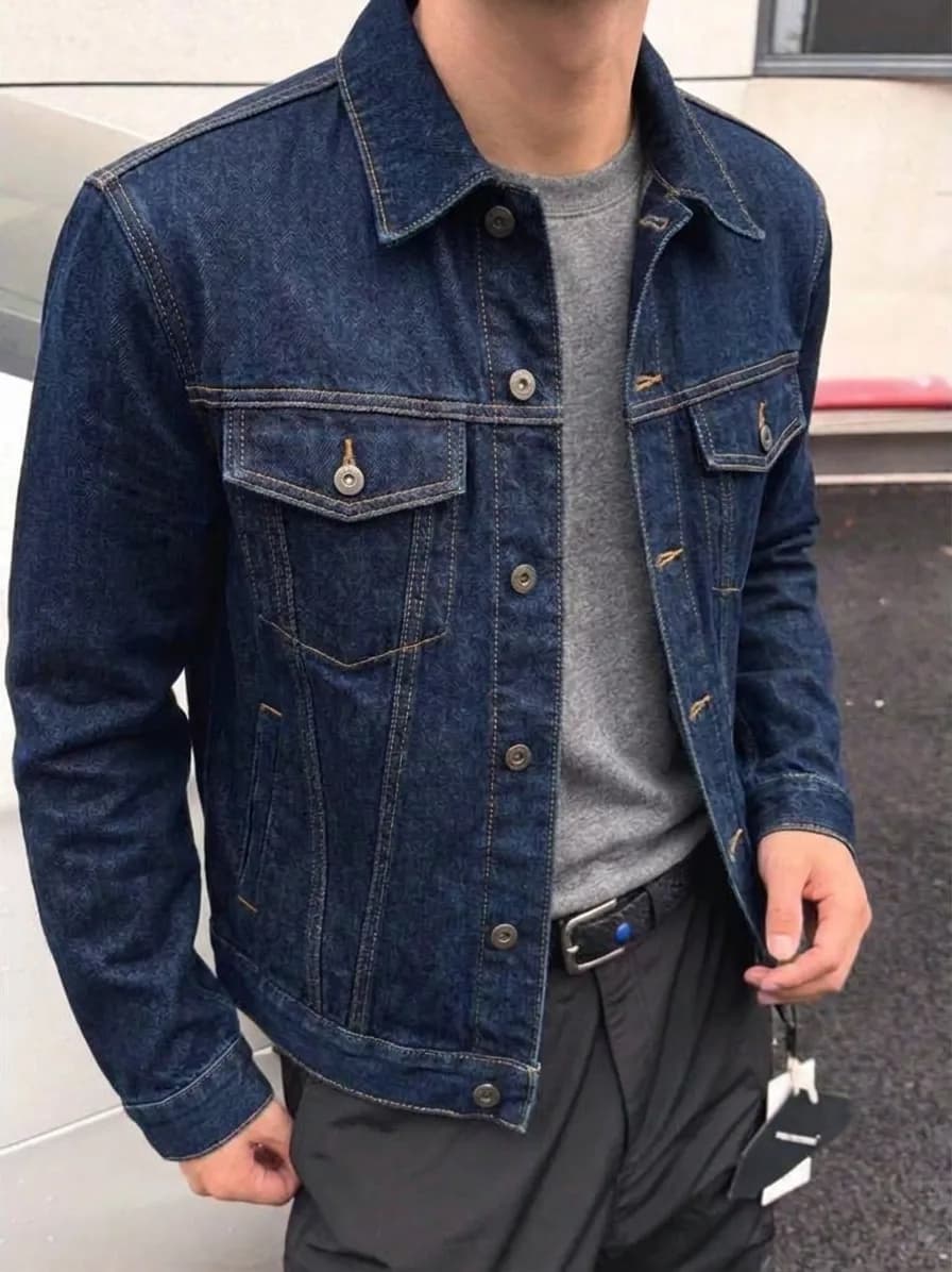 Dark indigo denim trucker jacket worn open over a grey T-shirt