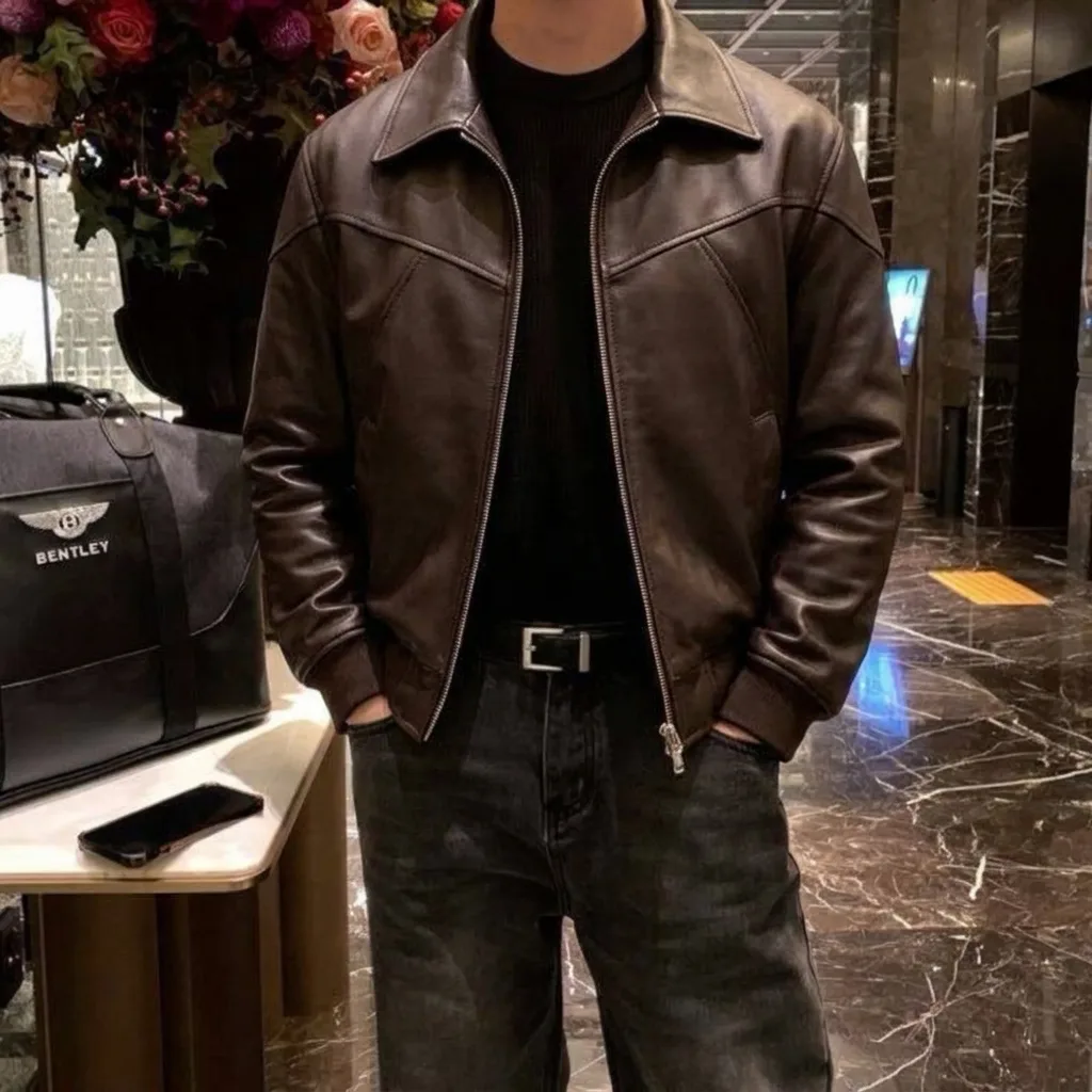 Brown leather jacket over a black knit, with dark jeans and a black belt