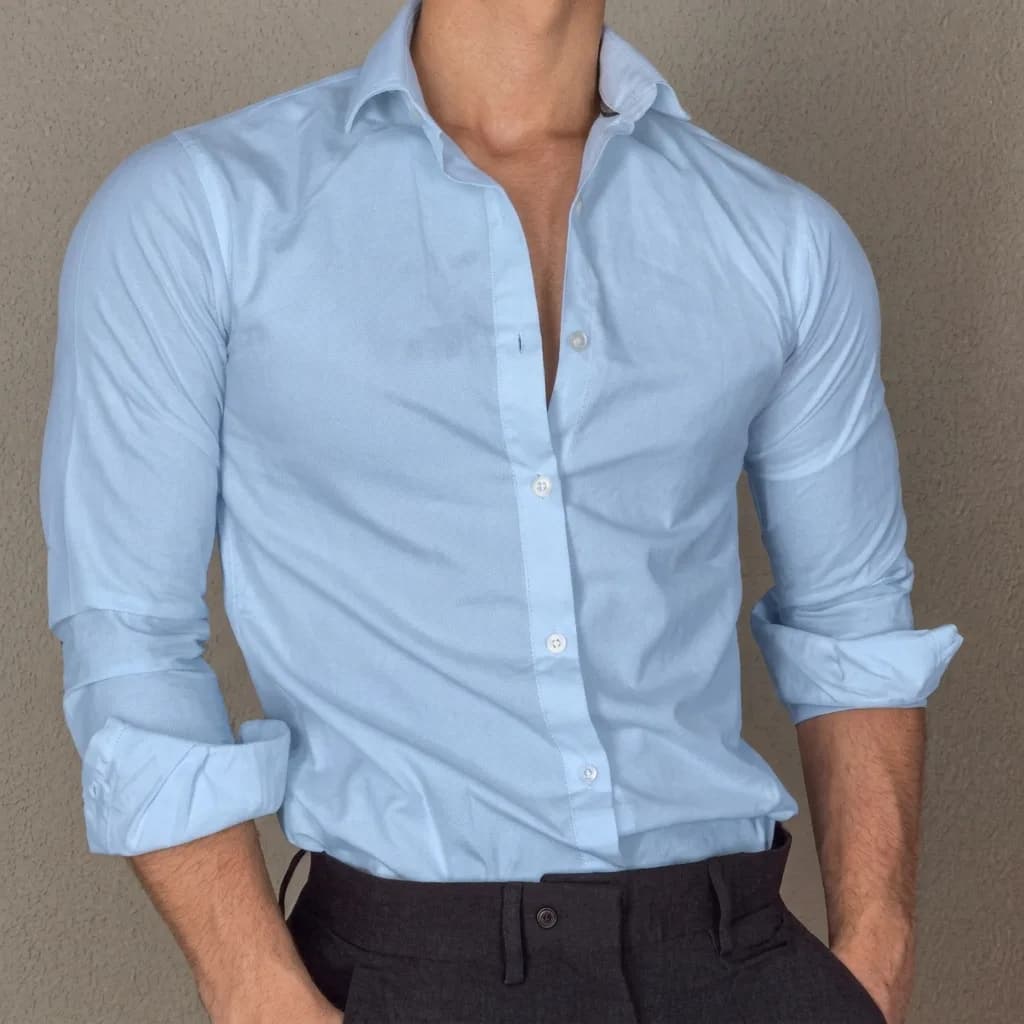 Light blue Oxford shirt with the sleeves rolled and the collar open, worn with dark trousers