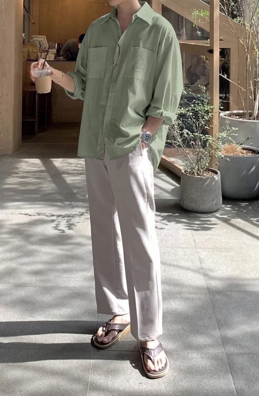 Sage green casual shirt with chest pockets and rolled sleeves, worn with light trousers and sandals