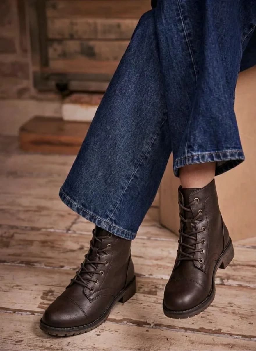 Brown lace-up ankle boots with a cap toe, worn with wide jeans