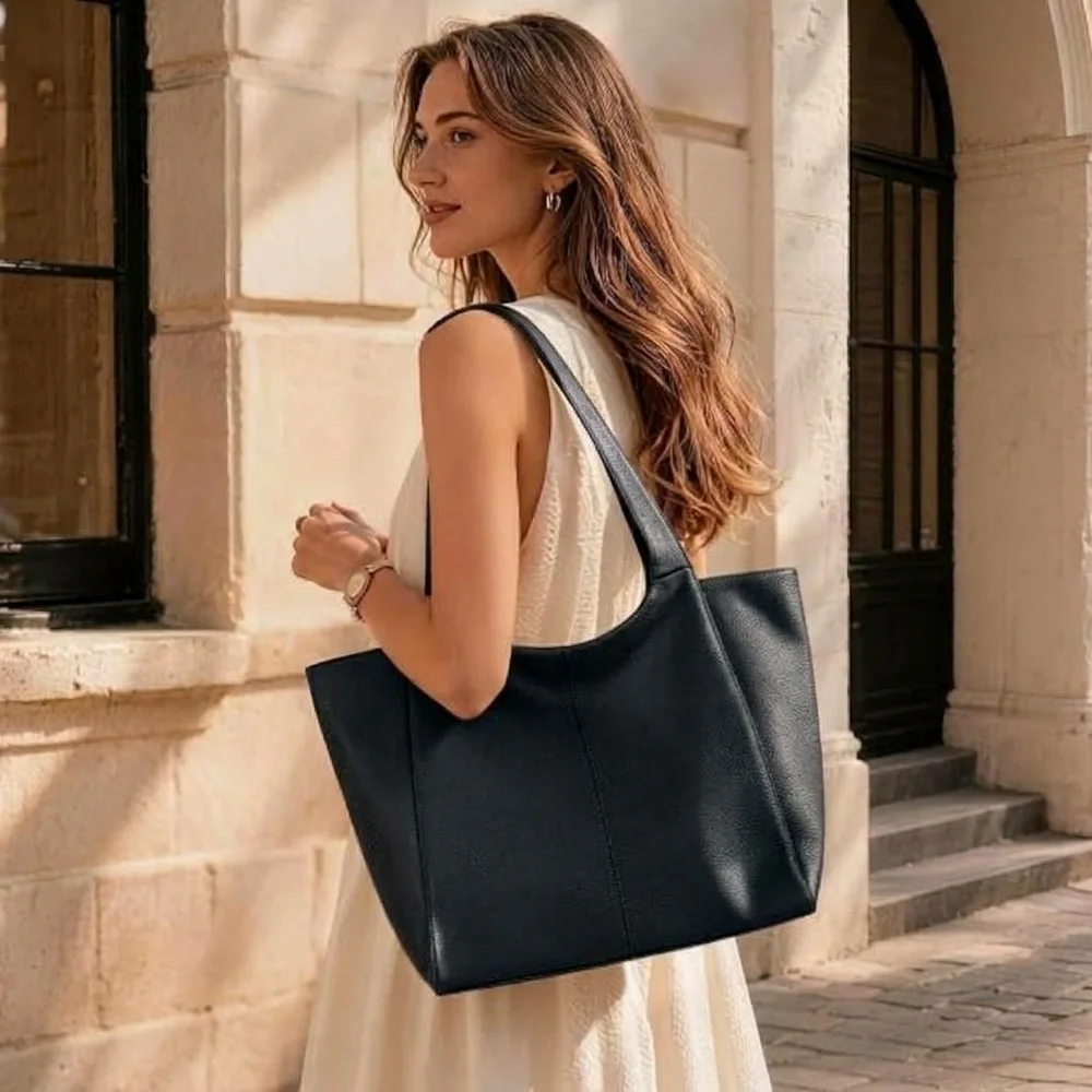 Large black leather tote carried on the shoulder with a cream dress