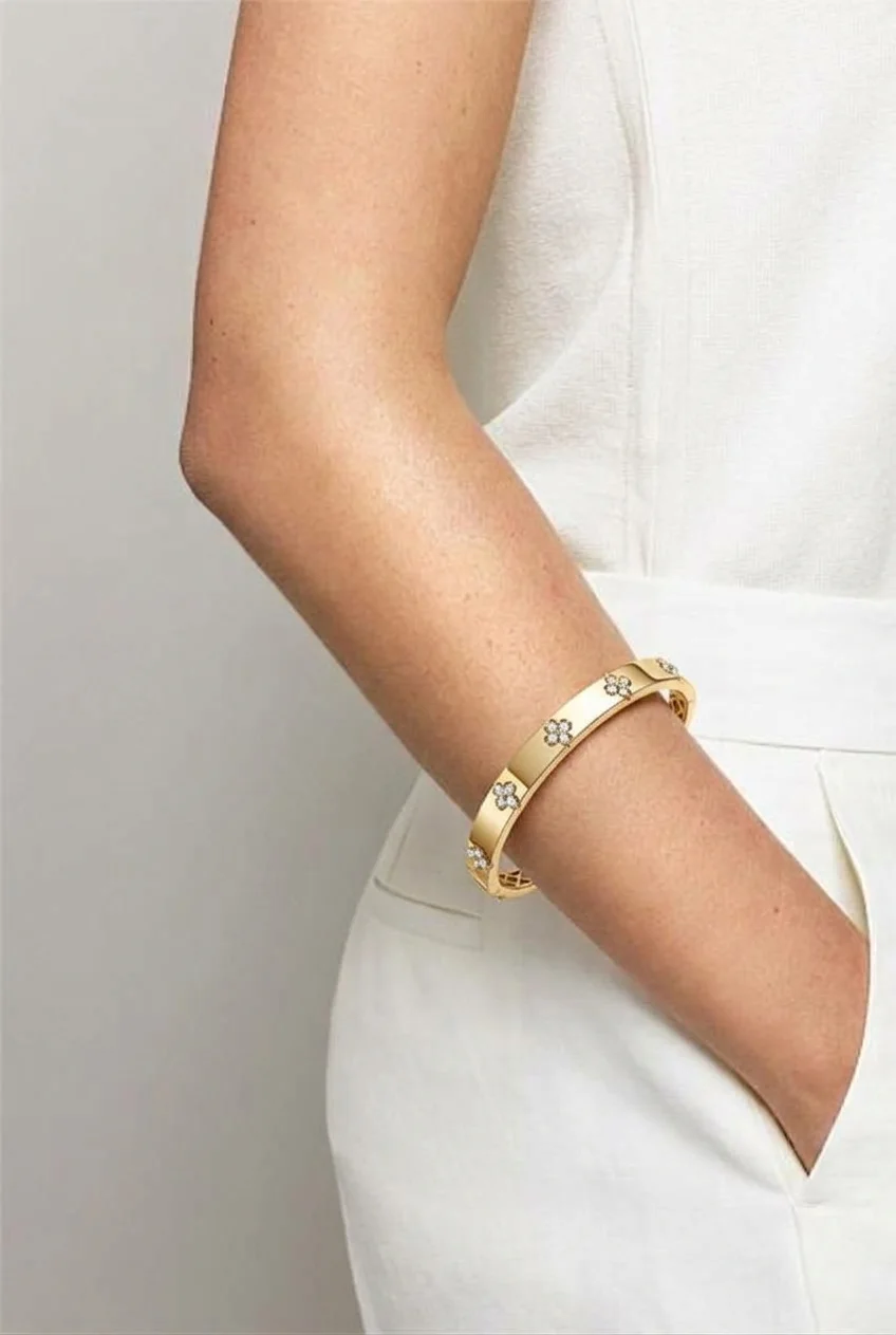 Gold bangle with small flower-shaped stones on a wrist
