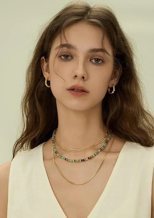Gold hoop earrings worn with layered necklaces