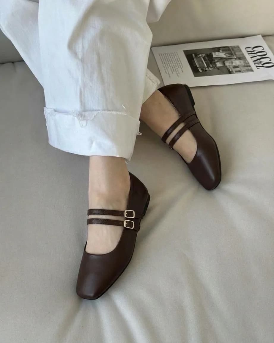 Brown square-toe Mary Jane flats with two buckle straps, worn with white trousers