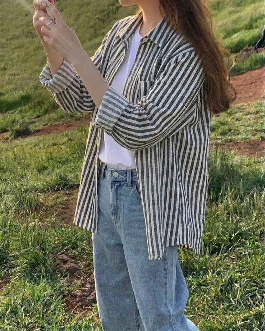 Black-and-white striped button-down worn open over a white t-shirt and light jeans