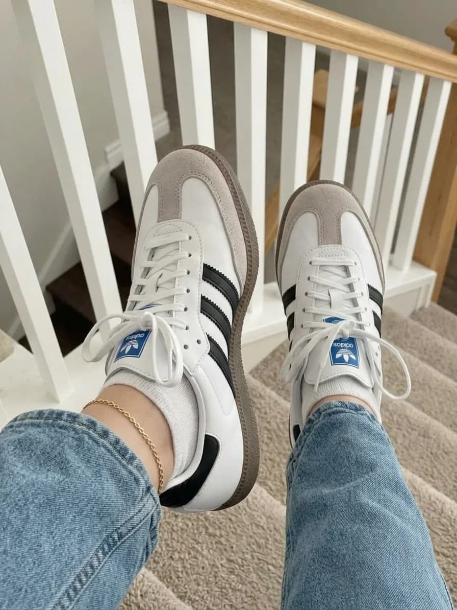 White low-top sneakers with black side stripes, grey overlays, and a gum sole