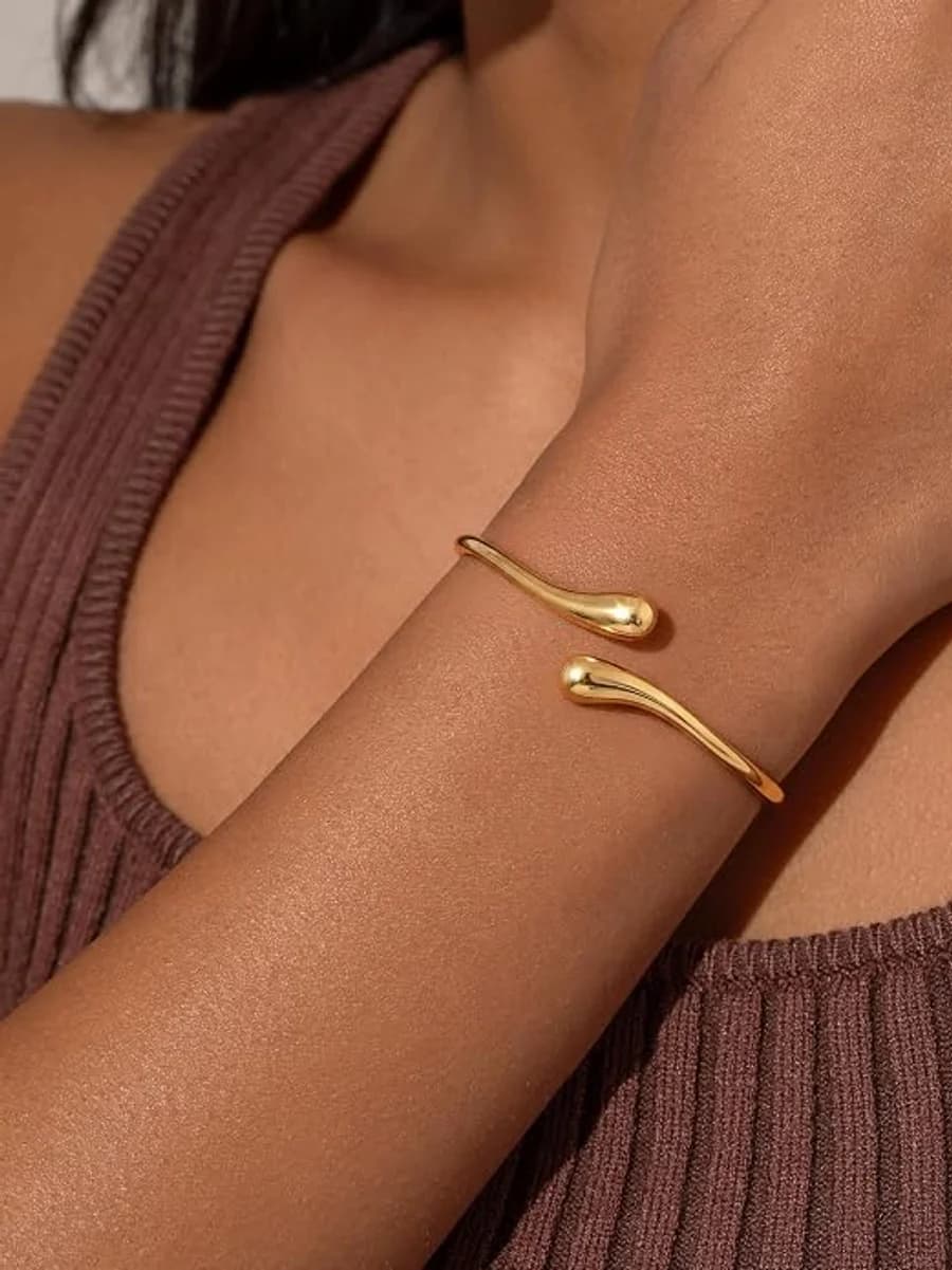 Slim gold open cuff bracelet with teardrop ends on a brown ribbed tank
