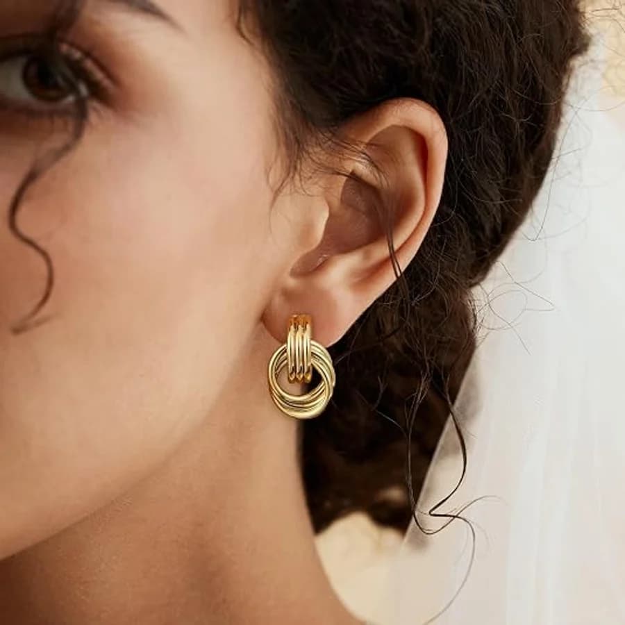 Three interlocking gold hoop earrings on a model with dark curly hair