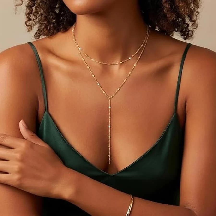 Layered gold lariat necklace with disc charms on a green silk camisole