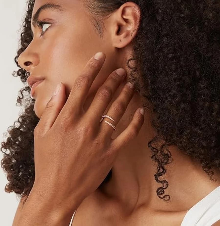 Delicate pavé crystal wrap ring on a ring finger against curly dark hair