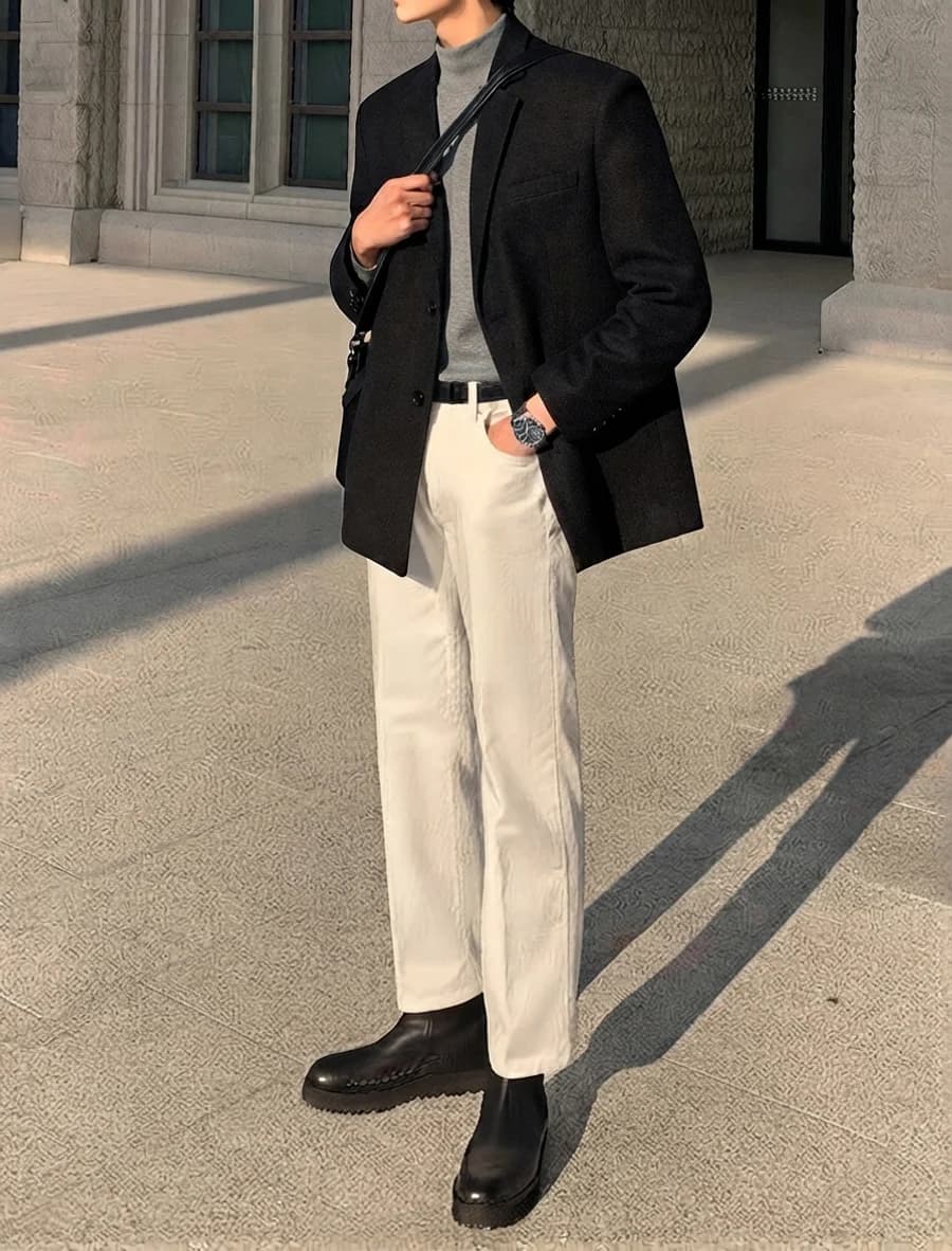 Night out tailoring: black blazer open over a grey mock-neck knit with cream trousers and black Chelsea boots
