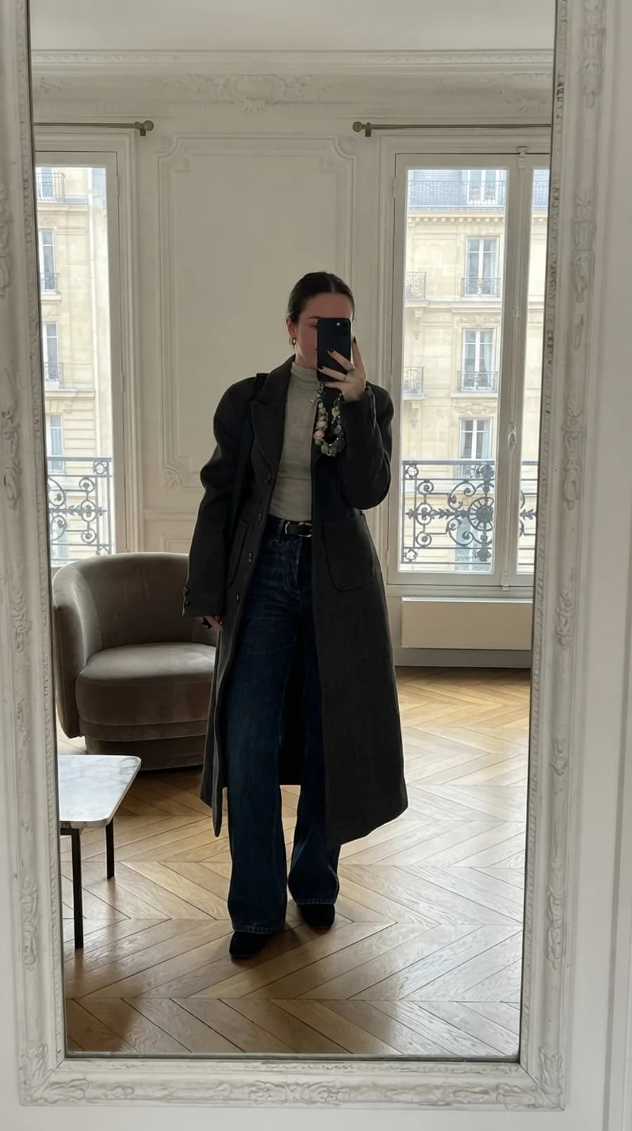 Street style layering: long charcoal wool coat open over a grey fine-knit turtleneck, high-waisted dark jeans and black boots