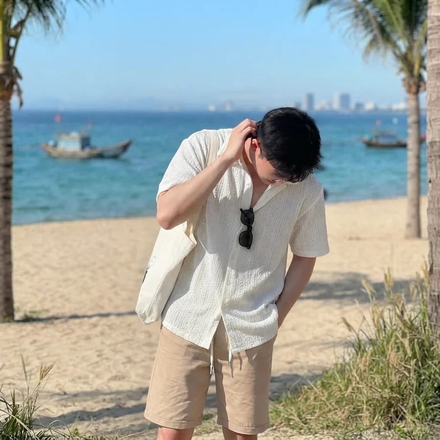 Men's summer style guide: off-white camp shirt with tan drawstring shorts on the beach