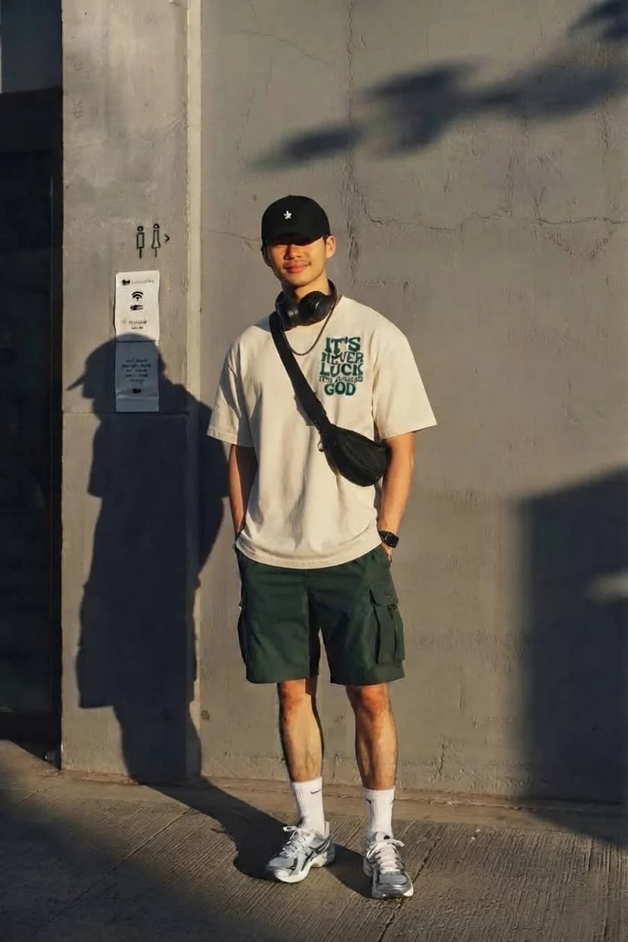 Men's summer outfit: oversized cream graphic tee with olive cargo shorts and white sneakers