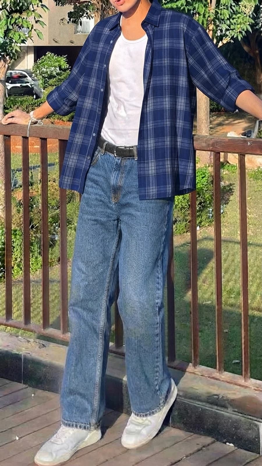 Men's summer outfit: navy plaid shirt open over a white tank with straight jeans