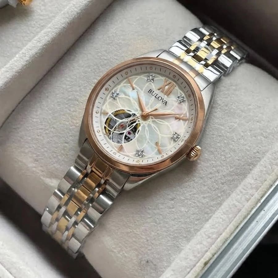 Women's two-tone gold and silver link bracelet watch with a cream ribbed sweater