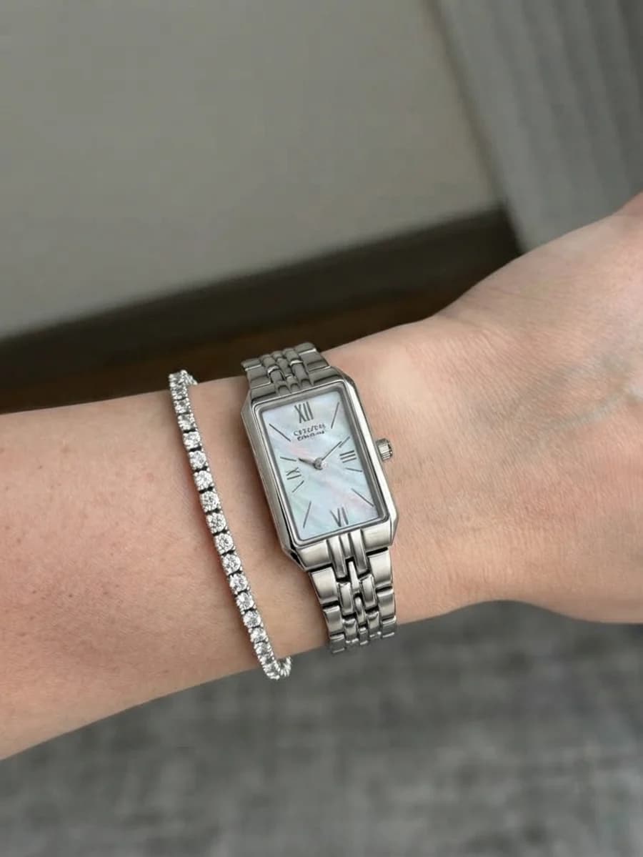 Slim rectangular mother-of-pearl dress watch stacked with a tennis bracelet